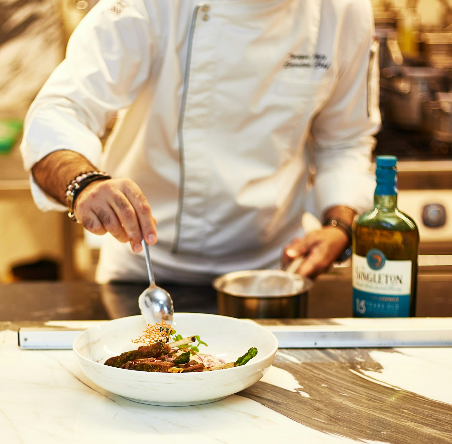 Chef plating a gourmet dish of meat and asparagus.