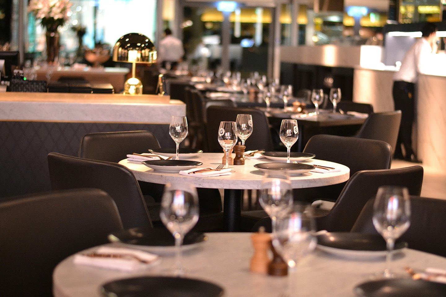 Elegant restaurant dining room with marble tables and leather chairs.