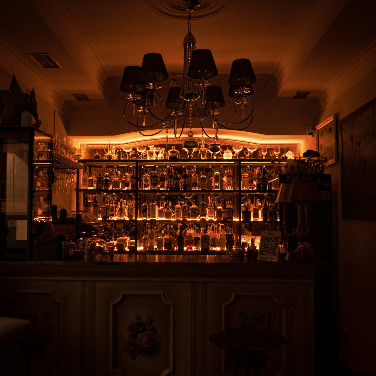Rows of alcohol bottles line a dark wooden bar counter.
